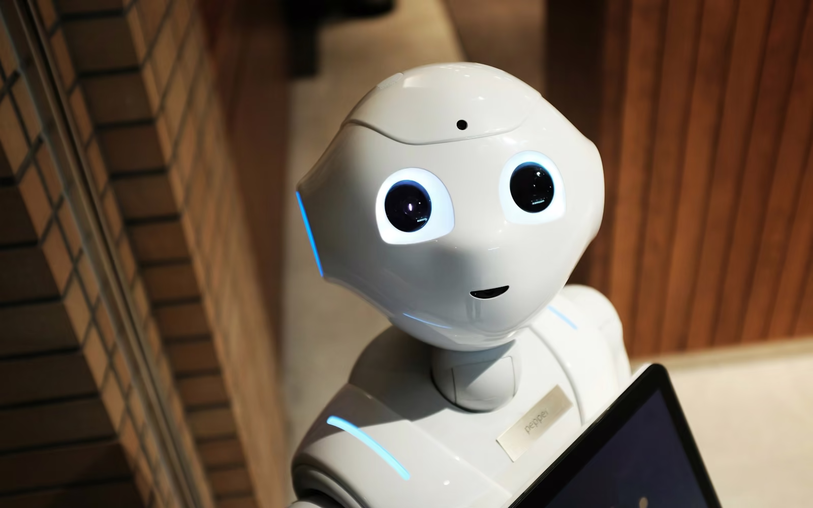 Robot putih berwajah ramah memegang sebuah tablet
