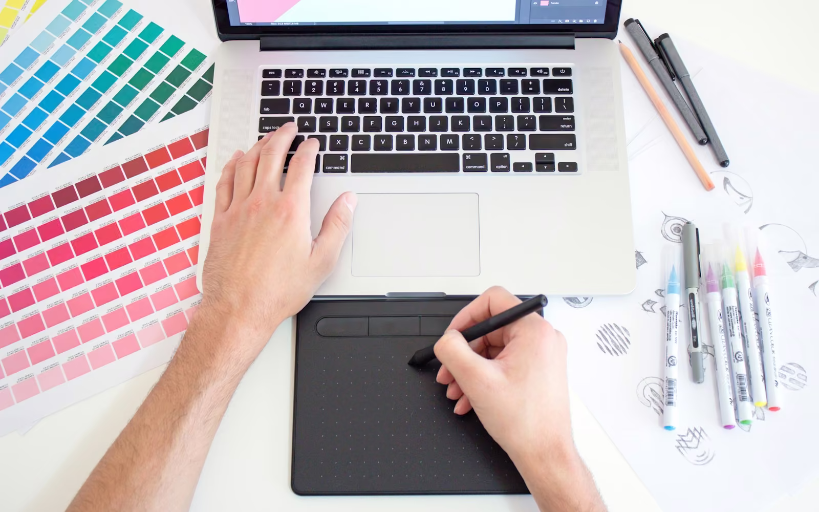 Tangan menggambar dengan pen tablet di dekat contoh palet warna dan laptop