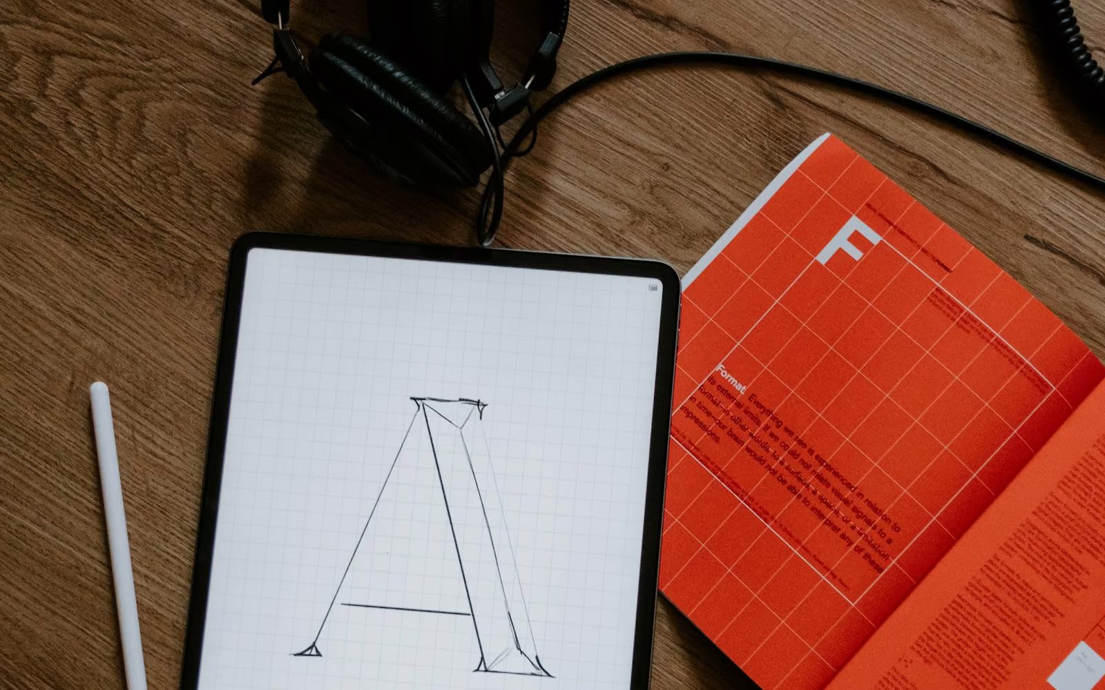 Tablet bergambar huruf A di samping buku bergaya desain