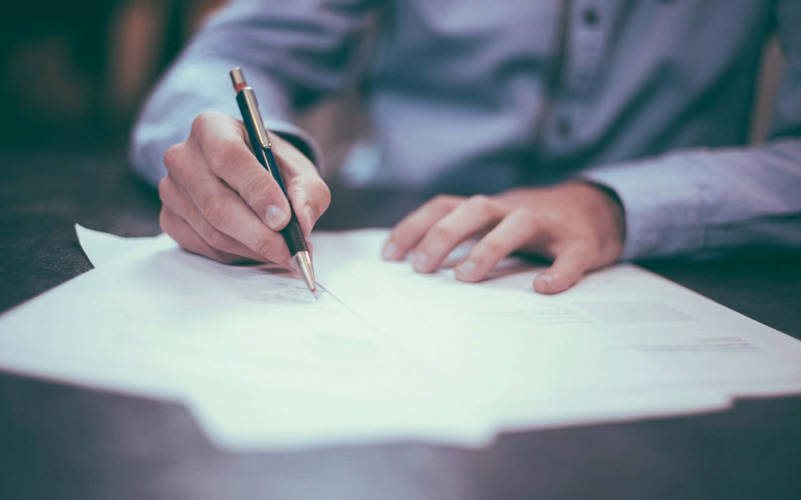 Tangan menulis dengan pulpen di atas selembar kertas