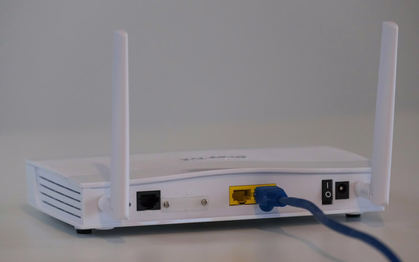 Router Wi-Fi putih dengan antena dilihat dari belakang