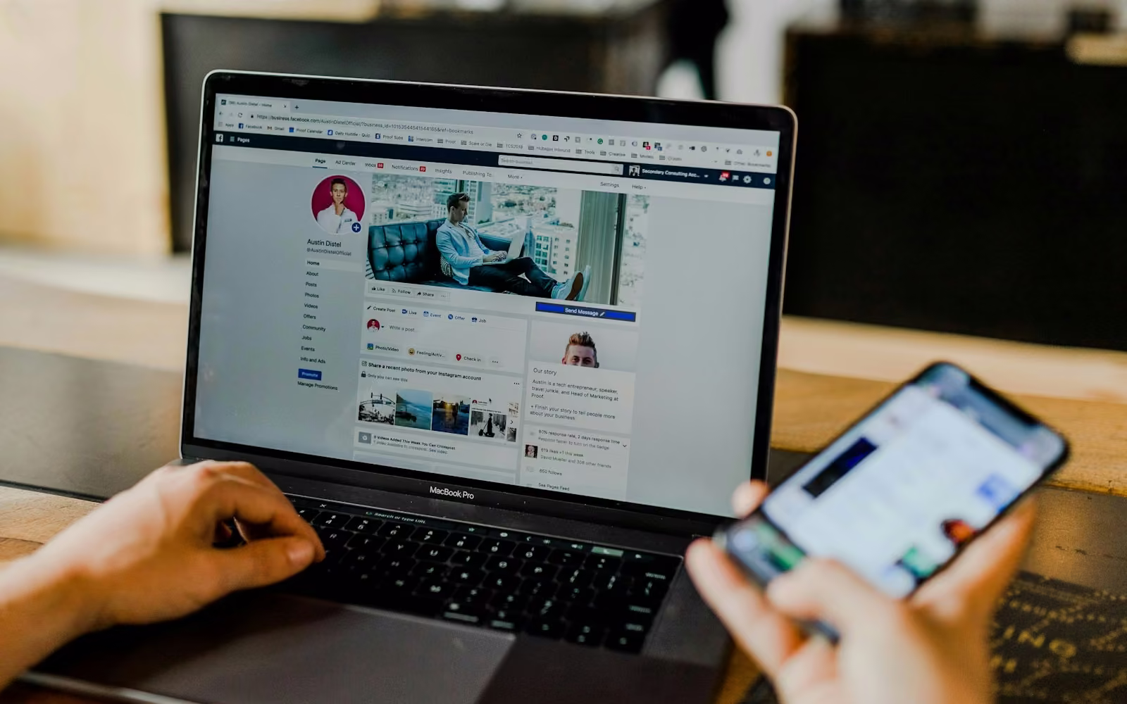 Seseorang membuka profil media sosial di laptop sambil memegang ponsel