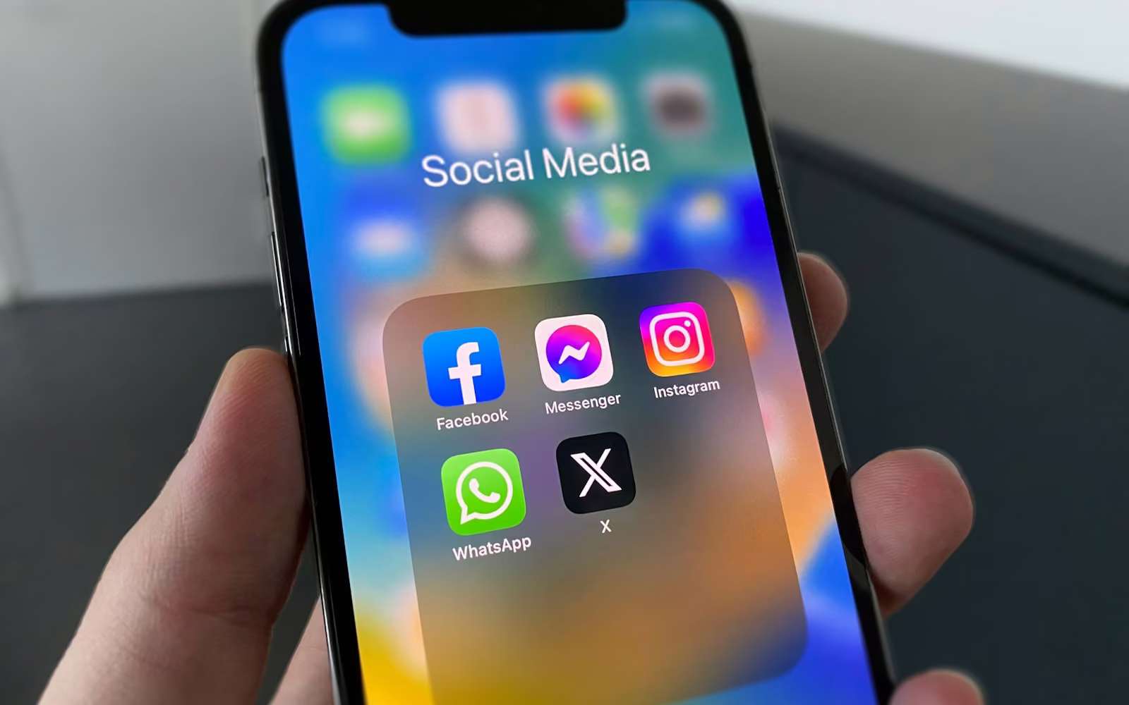 Tangan memegang ponsel berisi folder aplikasi media sosial
