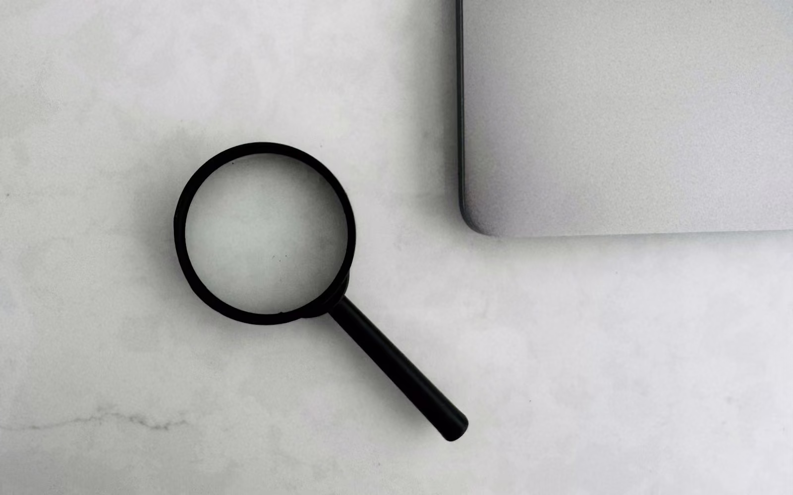 Kaca pembesar di samping laptop di atas meja